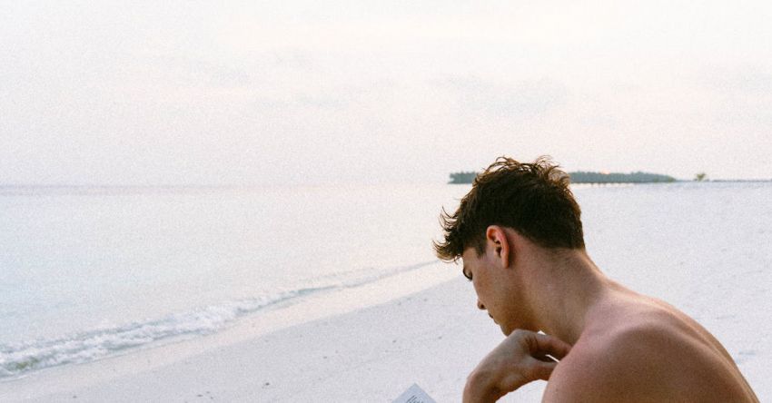 Books - Topless Man Reading Book While Seating at Beach