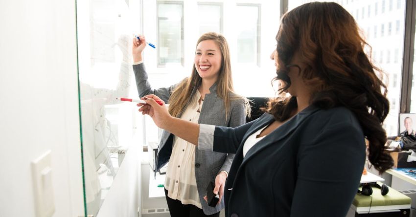 Workplace - Two Women in Front of Dry-erase Board