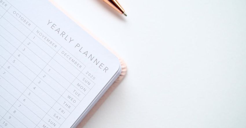 Planner - Close-Up Photo of Yearly Planner Beside a Pen